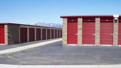 Outdoor drive up access storage units at Alice's Attic Self Storage with mountains in the background.
